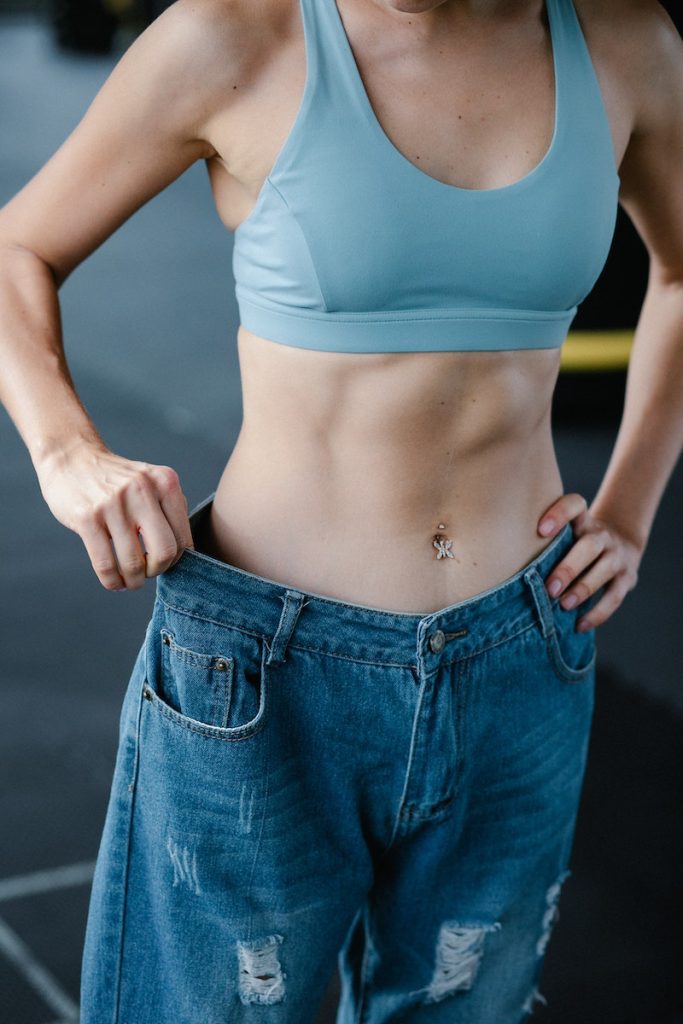 flat belly Toned Woman in Loose Pants Showing Diet Results